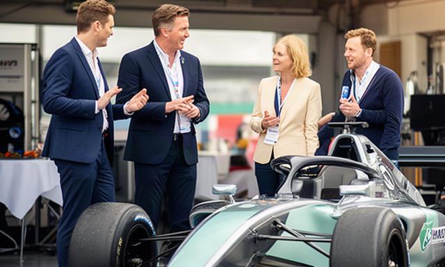 Zakelijke gasten in gesprek bij een racewagen tijdens een regionaal partnerweekend